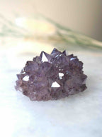 Gros plan sur une fleur d'améthyste brute, pointes de quartz violet déployées comme des pétales, spécimen unique