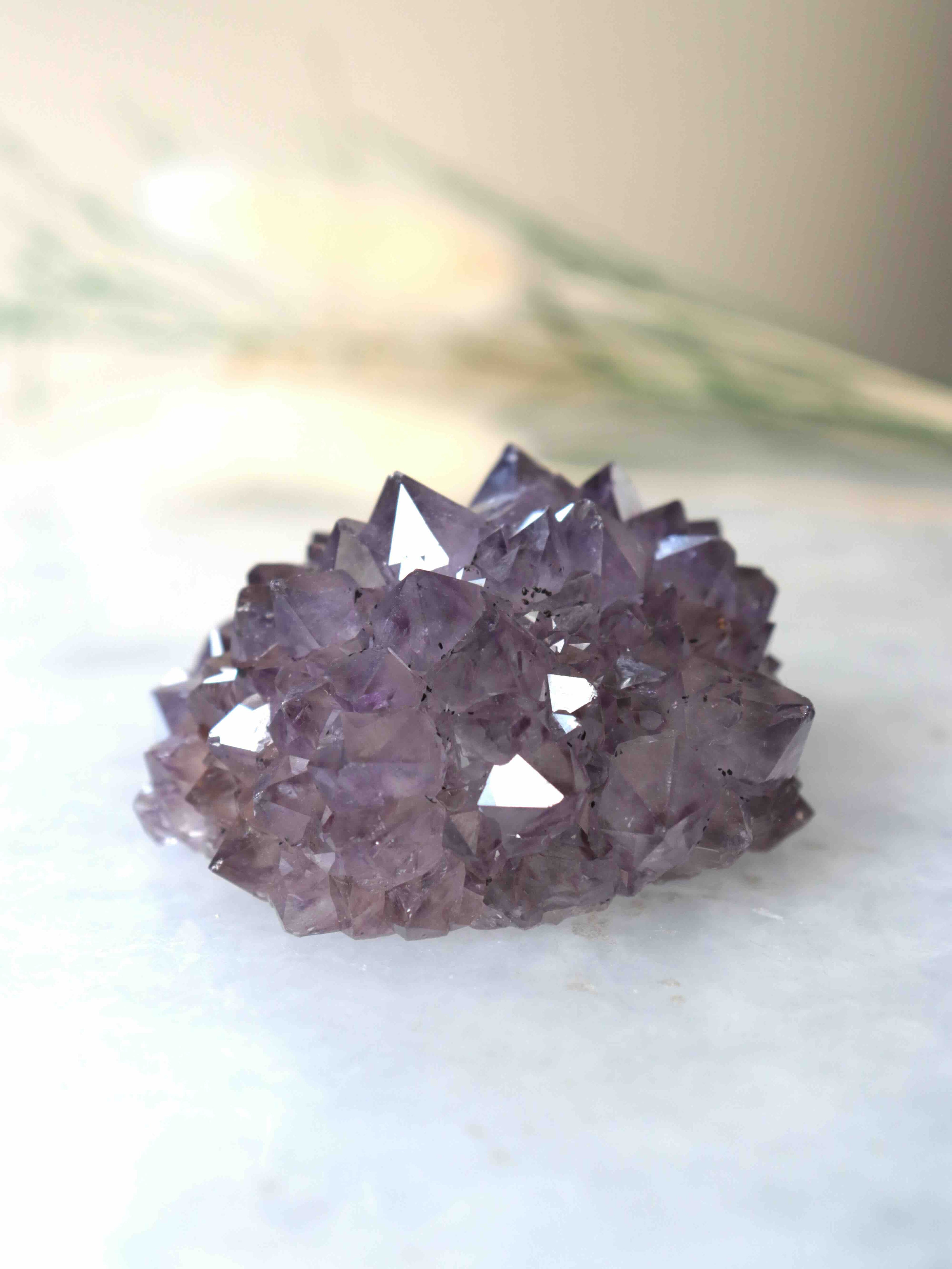 Gros plan sur une fleur d'améthyste brute, pointes de quartz violet déployées comme des pétales, spécimen unique