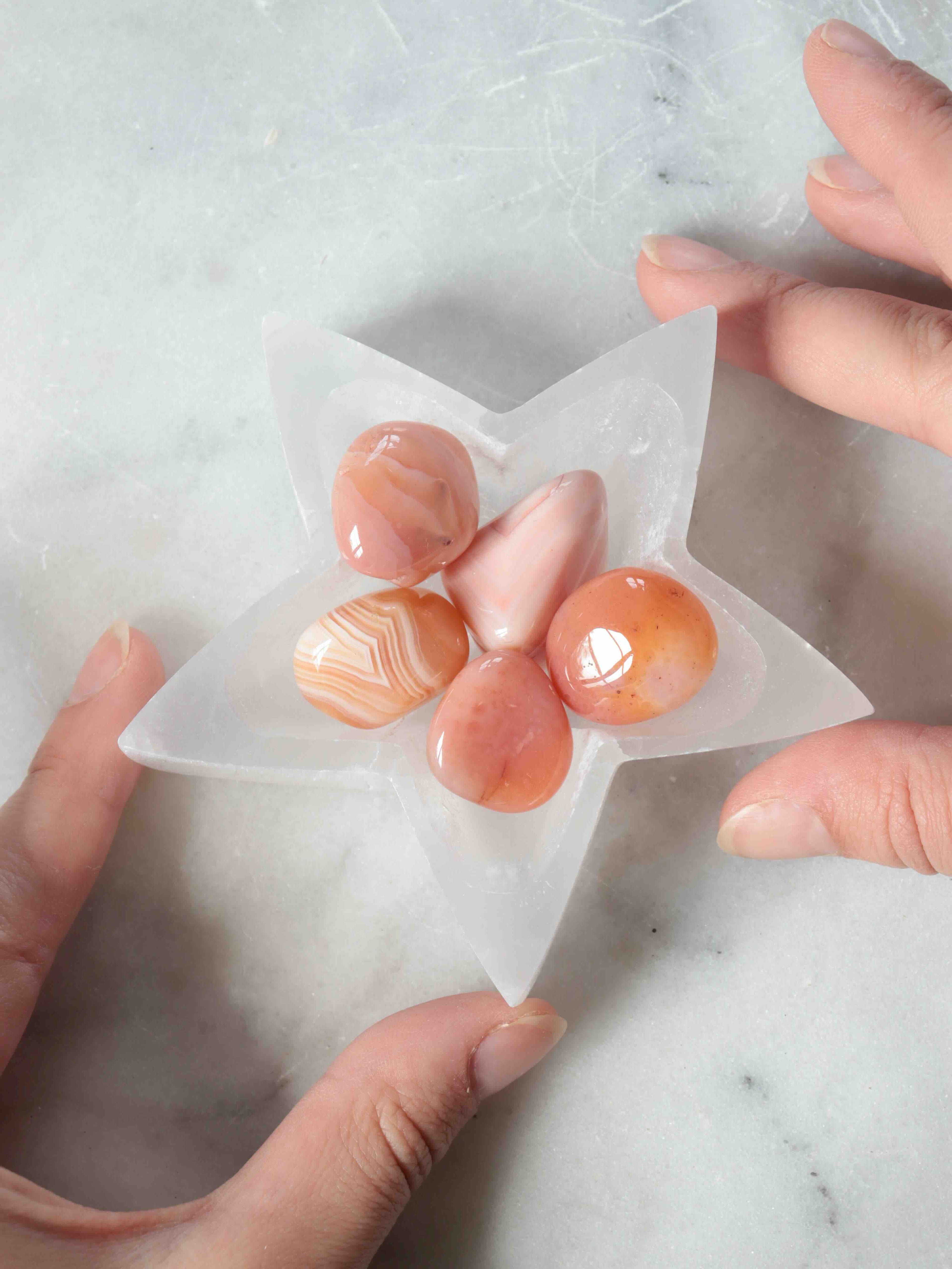 Coupelle étoile en sélénite tenue dans les mains avec pierres – cornaline, agate et quartz rose – bol de recharge SOLYA