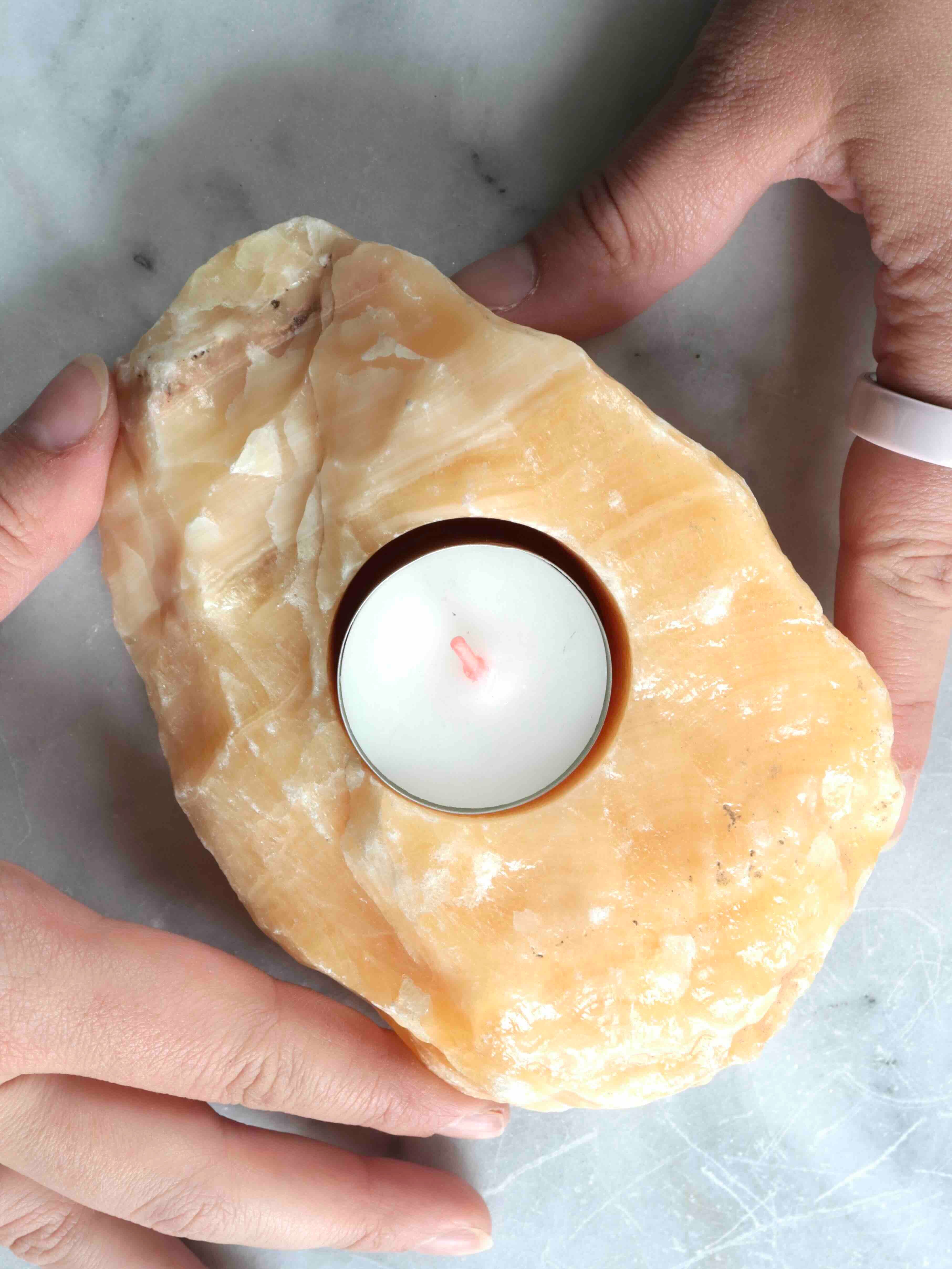 Bougeoir en calcite orange brute tenu dans les mains – taille et texture naturelle unique – pierre éthique SOLYA Belgique