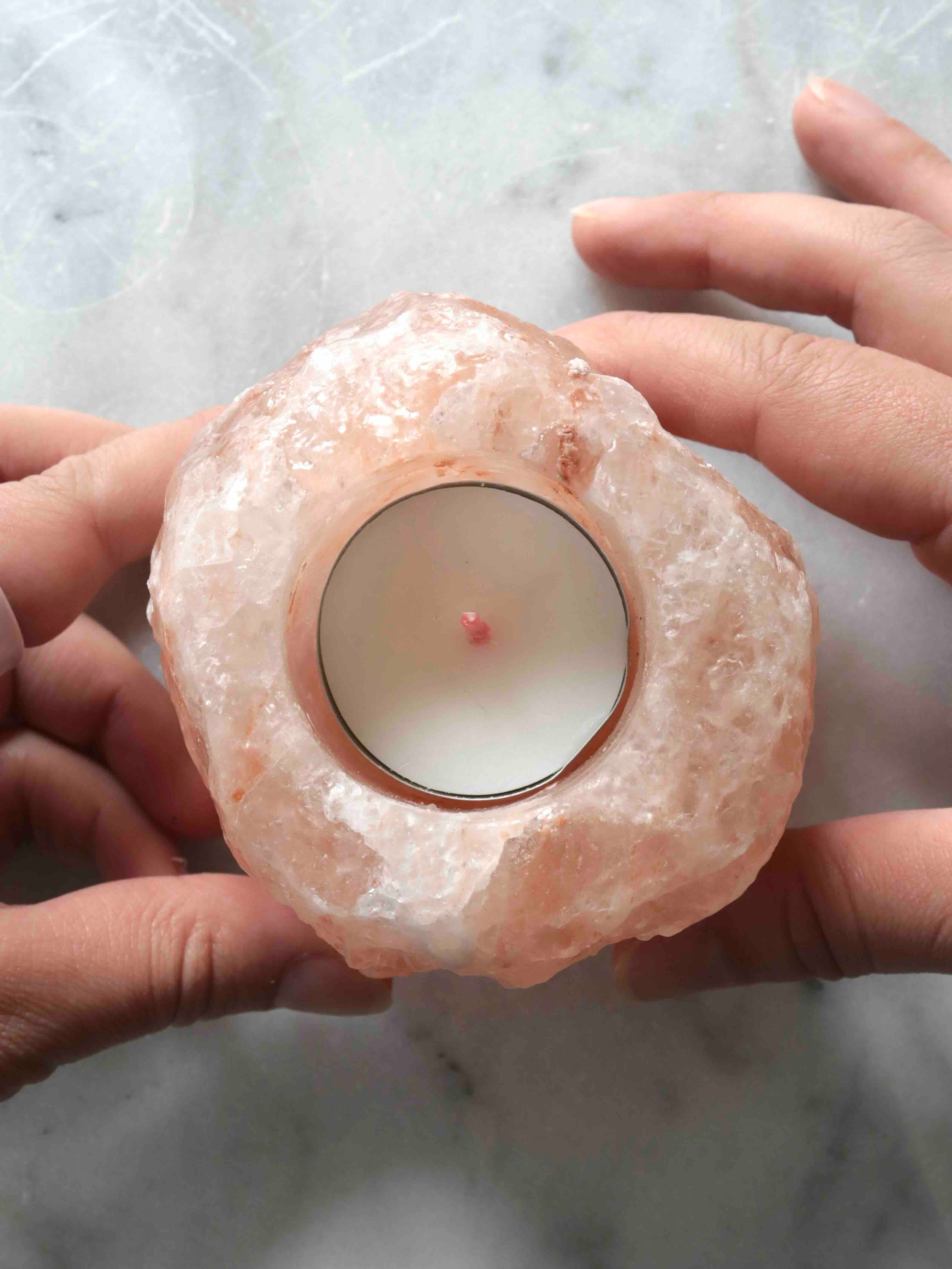 Bougeoir en halite brute tenu dans les mains – texture cristalline naturelle rose et blanche – pierre de sel SOLYA Belgique