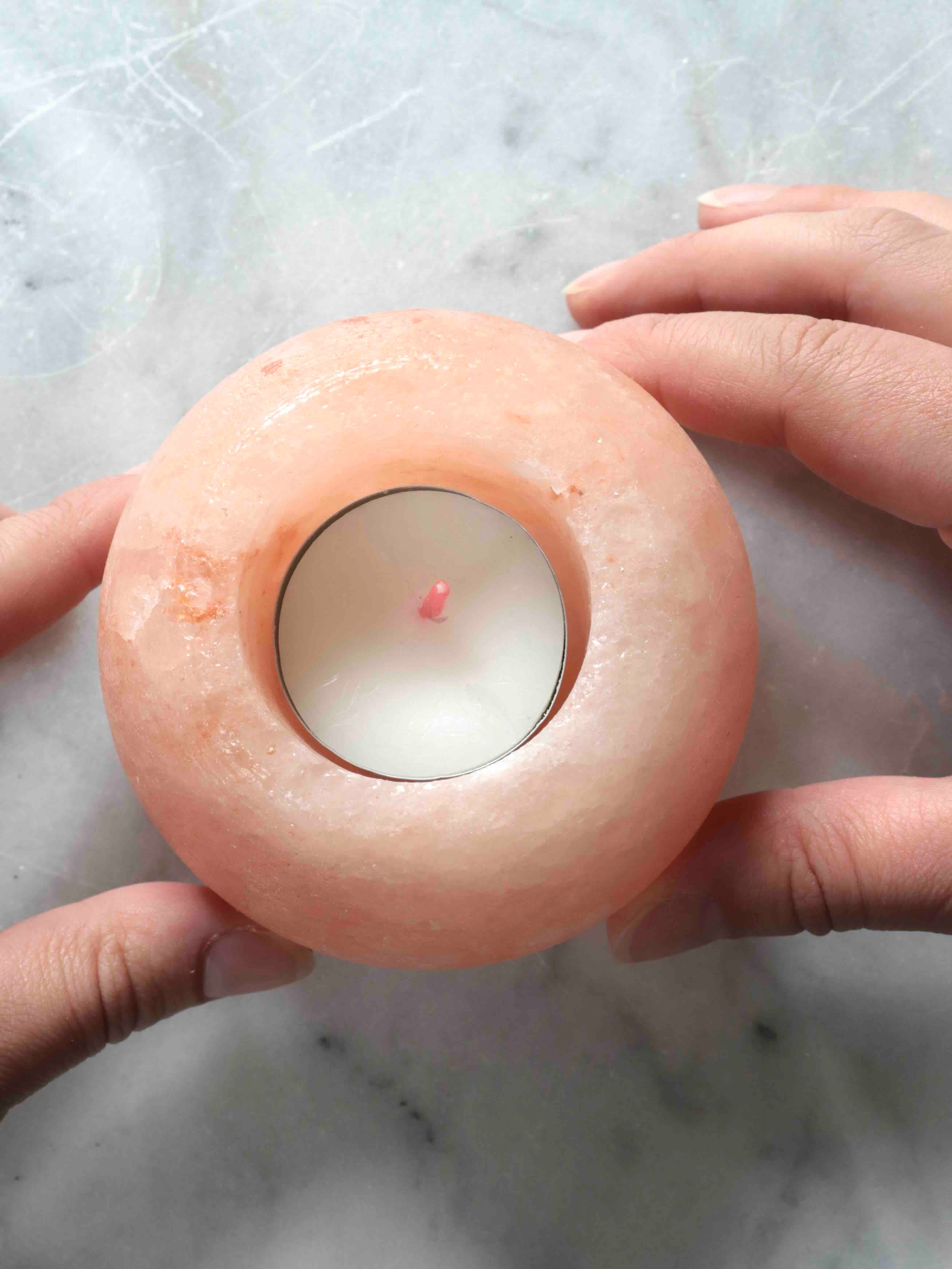 Bougeoir en halite rose tenu dans les mains – taille et texture cristalline naturelle – pierre de sel SOLYA Belgique