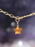 Charm étoile en Œil-de-Tigre taillé main suspendu à une chaîne Gold-filled 14K SOLYA — reflets dorés ambrés sur fond sombre