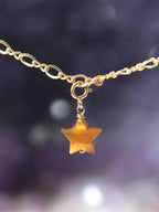 Charm étoile en Œil-de-Tigre taillé main suspendu à une chaîne Gold-filled 14K SOLYA — reflets dorés ambrés sur fond sombre