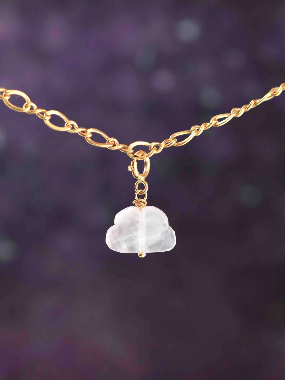 Charm nuage en quartz rose avec fermoir en gold-filled 14K, suspendu à une chaîne sur fond violet. 
