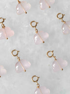 Charms nuages en quartz rose pâle avec attaches en gold-filled 14K, disposés sur fond clair.