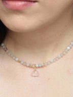 Charm nuage en quartz rose porté en pendentif sur un collier de perles aux teintes pastel.
