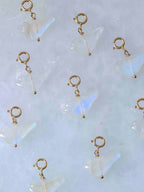  Charms oiseaux en pierre de lune aux reflets irisés, avec fermoirs en gold-filled 14K, disposés sur fond clair.