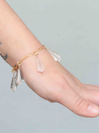Bracelet en Gold-filled 14K porté au poignet avec plusieurs charms mini Vogel en cristal de roche.