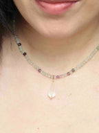 Charm mini Vogel en cristal de roche porté en pendentif sur un collier de perles multicolores.