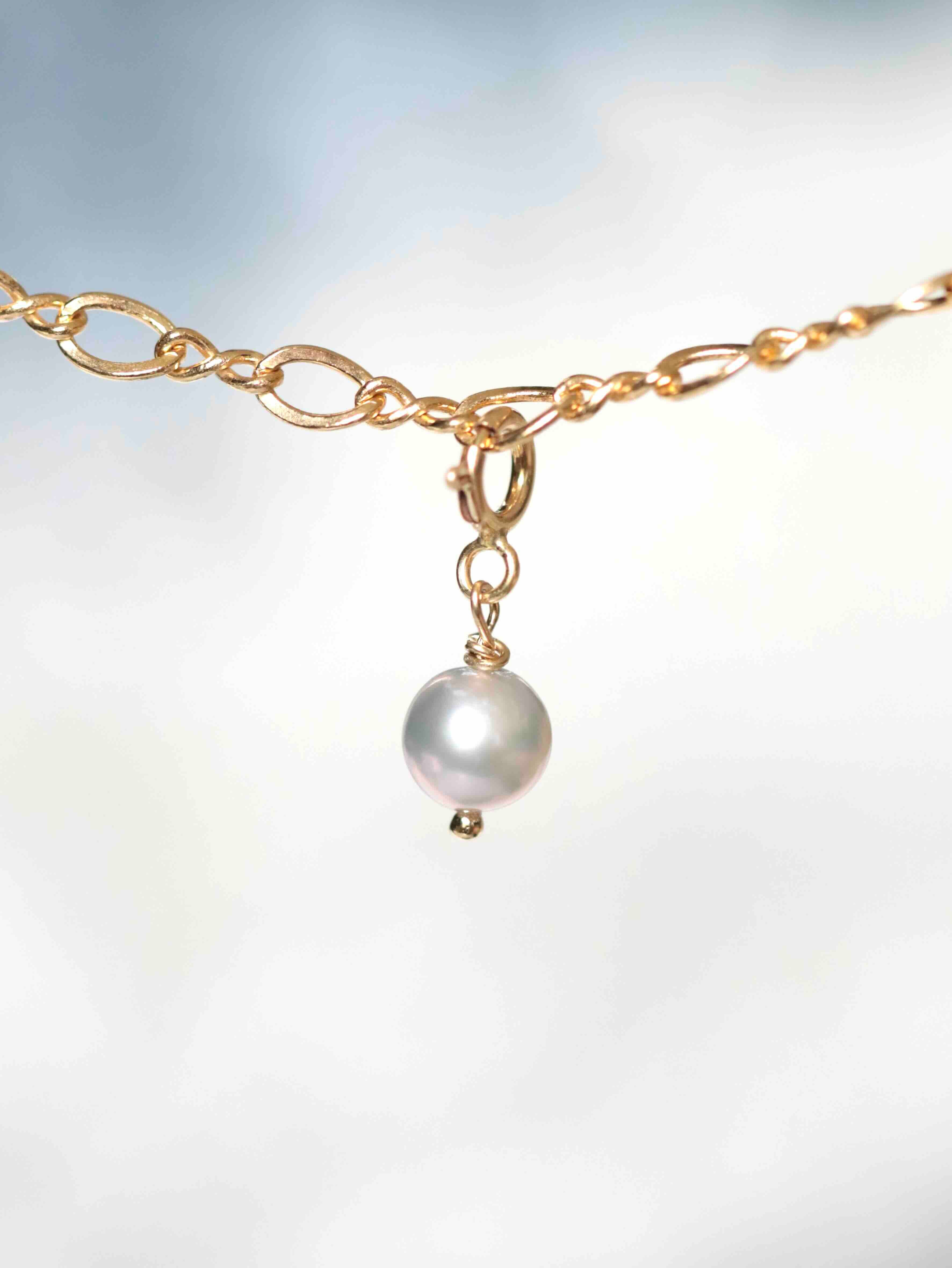 Gros plan sur le Charm Perle grise Gold-filled 14K — Pierre de circulation des énergies SOLYA