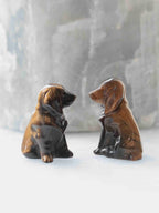  Deux chiens assis sculptés en œil-de-tigre, présentés de profil face à face sur un fond clair.