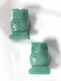 Deux chouettes sculptées en aventurine verte naturelle, vues de face, pierre polie vert menthe sur fond blanc texturé