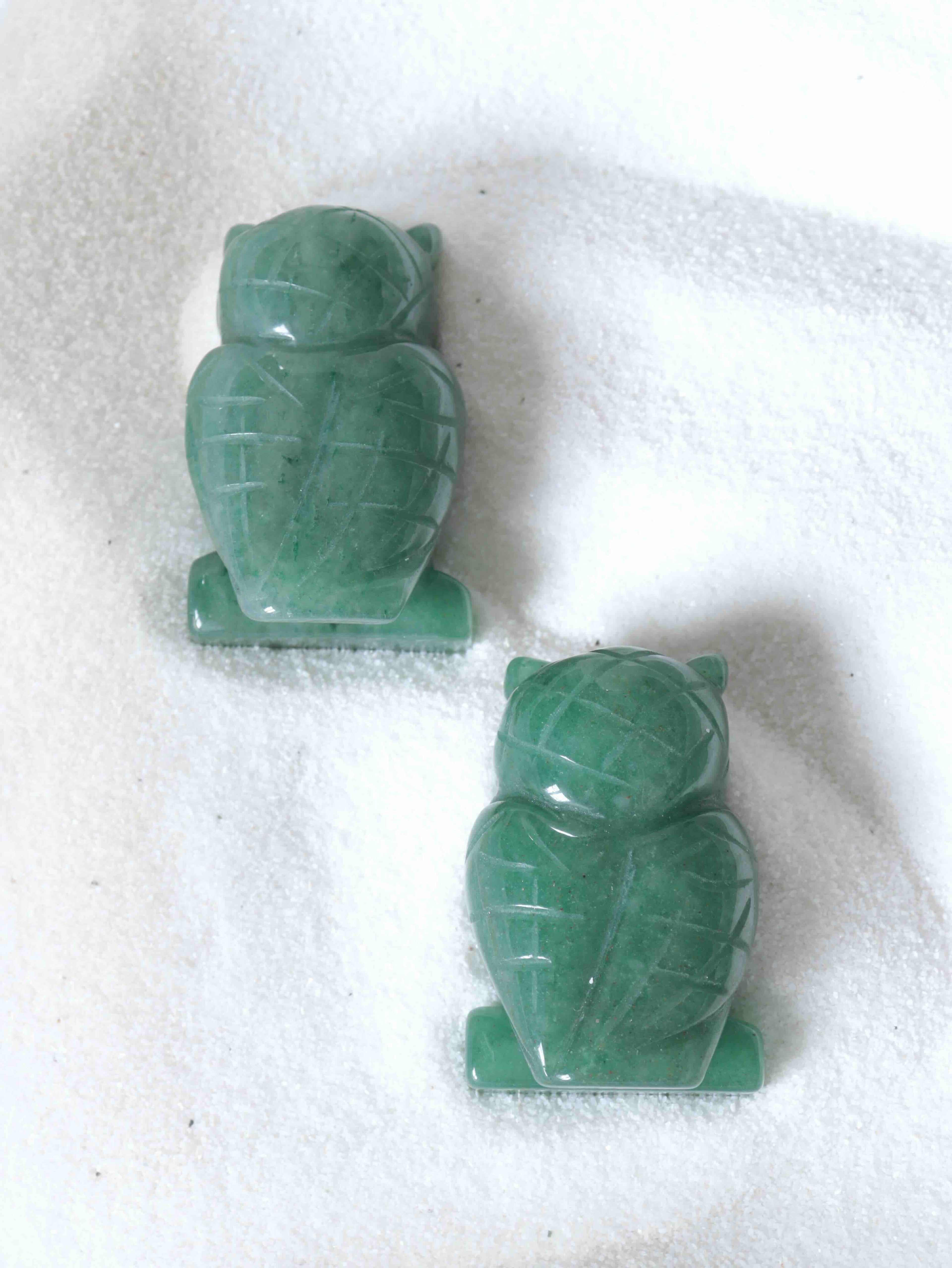 Deux chouettes en aventurine verte vues de dos, détails sculptés à la main, nuances vert tendre sur fond blanc