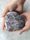 Grand cœur en lépidolite poli tenu en main, inclusions violettes et roses – pierre naturelle pour revenir à l'essentiel – SOLYA Belgique