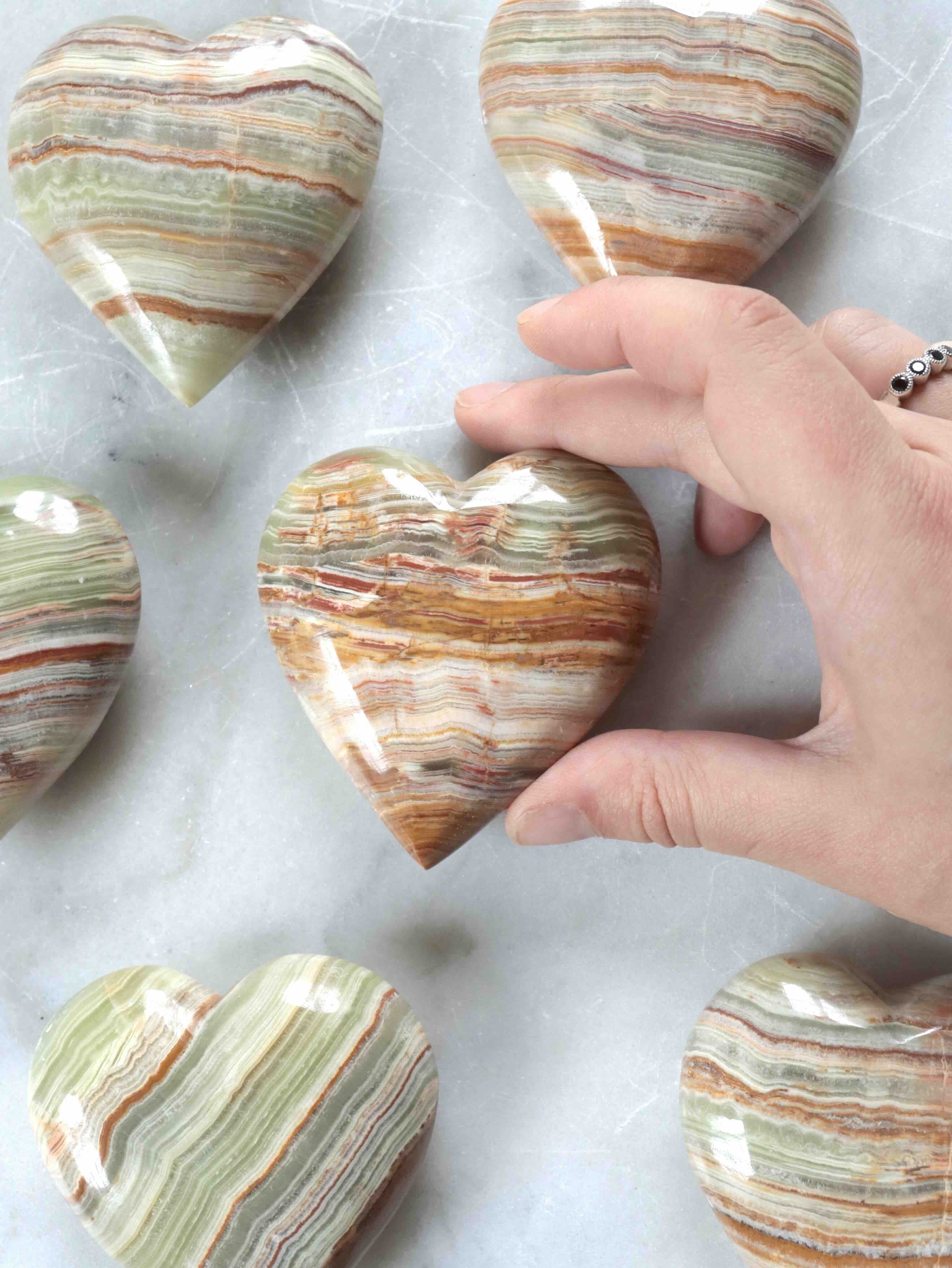 Cœur en aragonite saisi en main, taille réelle visible – pierre naturelle pour la paix intérieure – SOLYA Belgique