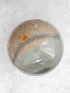 Sphère en jaspe polychrome aux bandes beige et gris-vert, avec une petite tache ocre sur la partie supérieure.