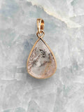 Pendentif en quartz dendritique en forme de goutte, aux inclusions noires ramifiées, serti d’argent 925 plaqué or, vu de face.