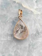 Pendentif en quartz dendritique en forme de goutte, aux inclusions noires ramifiées, serti d’argent 925 plaqué or, vu de face.