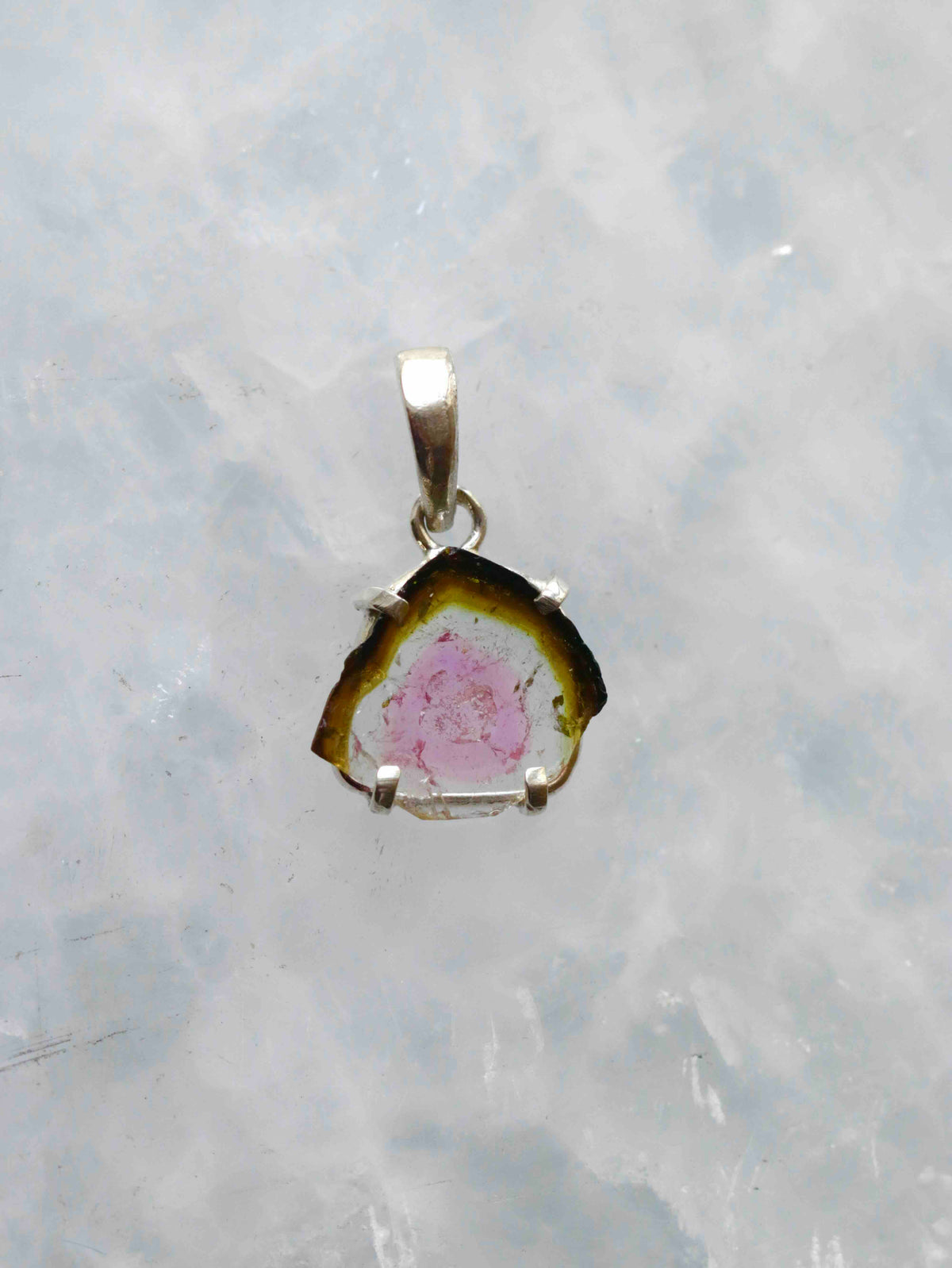 Pendentif en tranche de tourmaline melon d’eau au cœur rose et au pourtour vert foncé, serti à griffes en argent 925, vu de face.