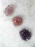 Trois fleurs d'améthyste moyenne côte à côte, teintes claire, rosée et foncée, pierres brutes du Brésil