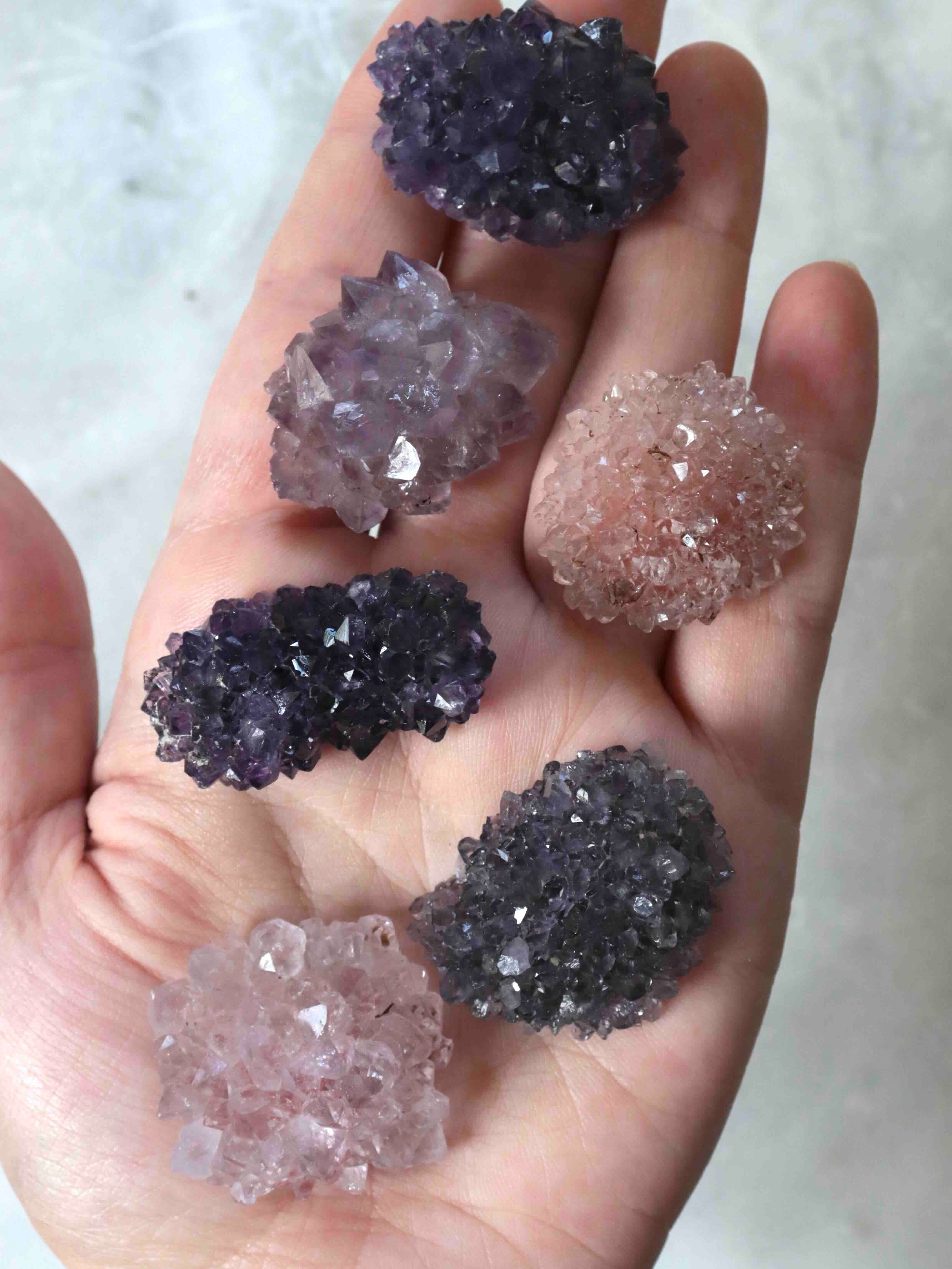 Mini fleurs d'améthyste posées sur fond neutre, reflets mauves lumineux, petites pièces de collection uniques SOLYA Belgique