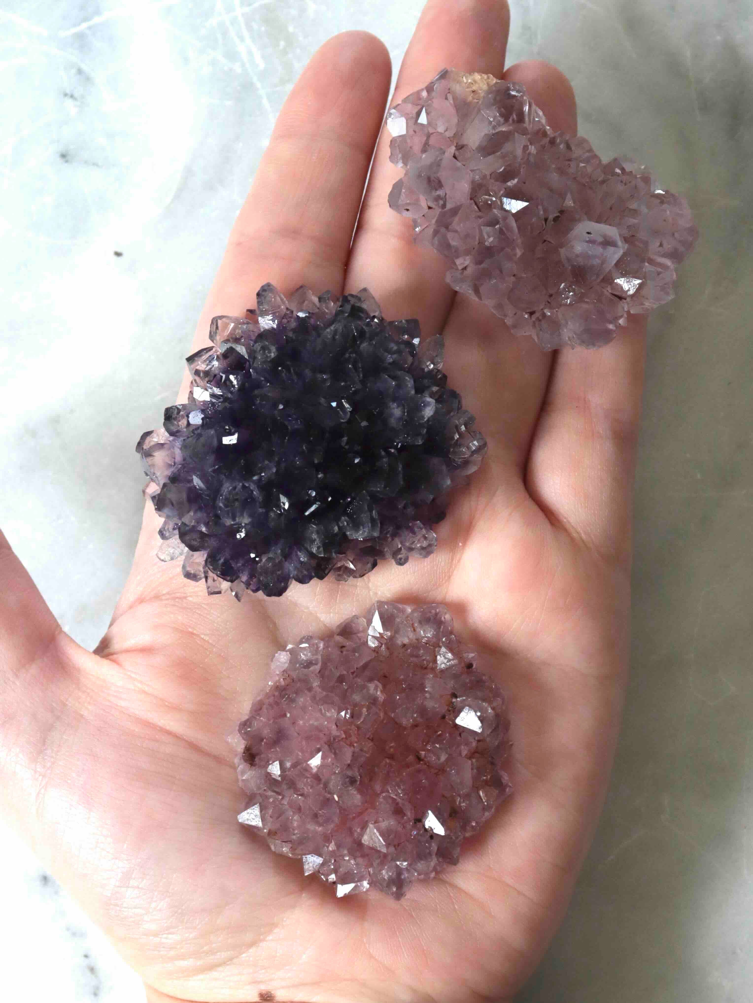 Trois fleurs d'améthyste moyenne côte à côte, teintes claire, rosée et foncée, pierres brutes du Brésil