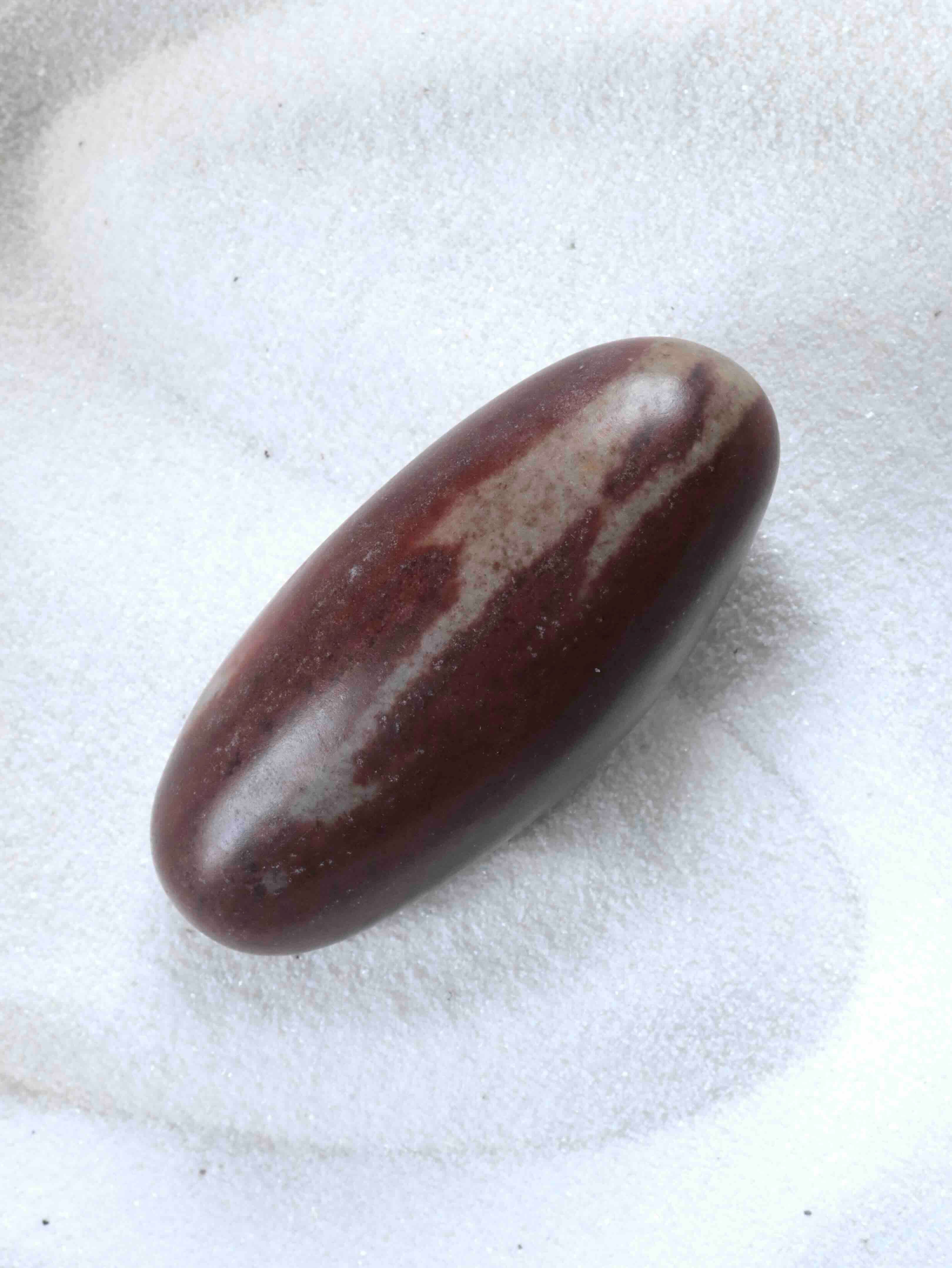 Shiva Lingam poli posé sur sable blanc – pierre naturelle pour l'harmonisation et l'amour universel – SOLYA Belgique